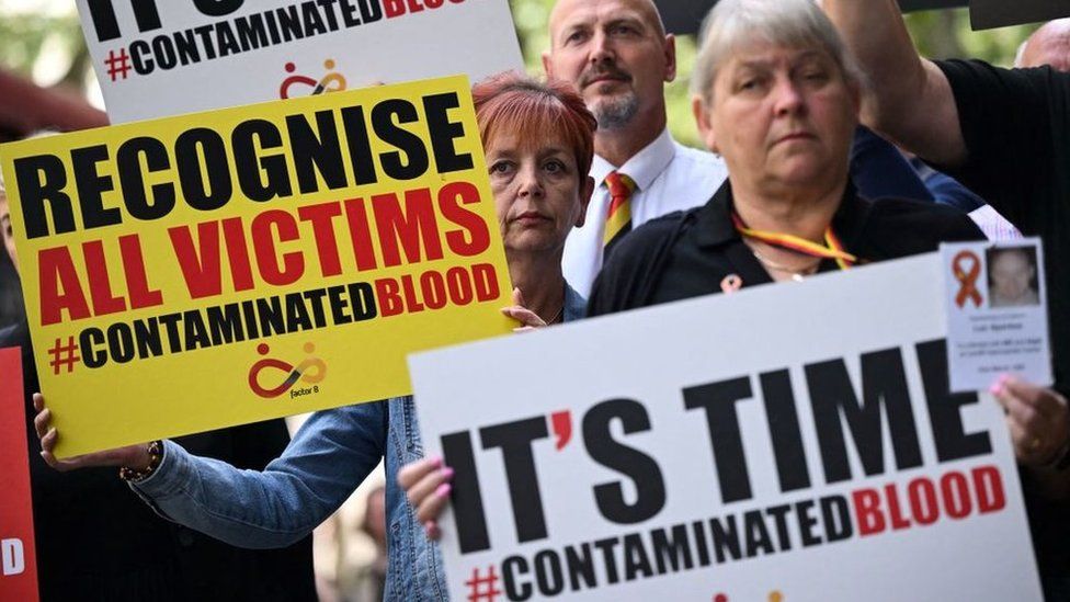 Protestors hold placards with message related to the NHS infected blood scandal as Prime Minister Rishi Sunak gives evidence to the Infected Blood Inquiry in London, on 26 July, 2023