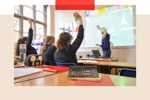 Getty Images Children putting their hands up in a classroom 